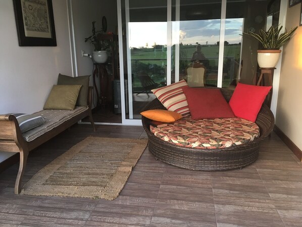 A cozy outdoor seating area with a wicker sofa and a wooden bench, both furnished with cushions. - Brotas Shangri-lá with 3 suites, pool and stunning views! (Caju)
