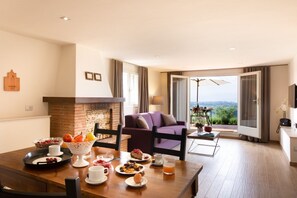 A dining area with a table set for breakfast, a fireplace, and a view of the outdoors. - Villa Tiziano. (San Gersolé-torre Rosse)