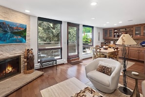 A modern living room with a fireplace, a dining area, and a kitchen.