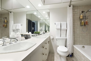 Une salle de bain moderne avec un grand miroir, deux lavabos, des toilettes et une baignoire.