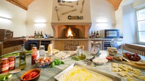 Een keuken met een bakstenen plafond, een open haard en diverse kookgerei en ingrediënten op het aanrecht.