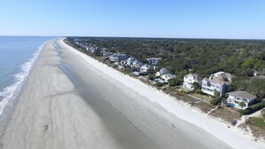 Een kustgebied met woonhuizen direct aan het strand, een zandstrand en weelderige begroeiing.