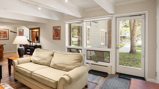 A living room with a beige sofa, a lamp, and a door leading outside. - Cottonwoods by iTrip Aspen Snowmass (Aspen)