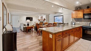 A spacious kitchen with wooden cabinets, a granite countertop, and a large island. - Cottonwoods by iTrip Aspen Snowmass (Aspen)