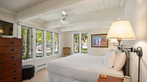 A bedroom with a large bed, a wooden dresser, a desk, a lamp, and a TV. - Cottonwoods by iTrip Aspen Snowmass (Aspen)