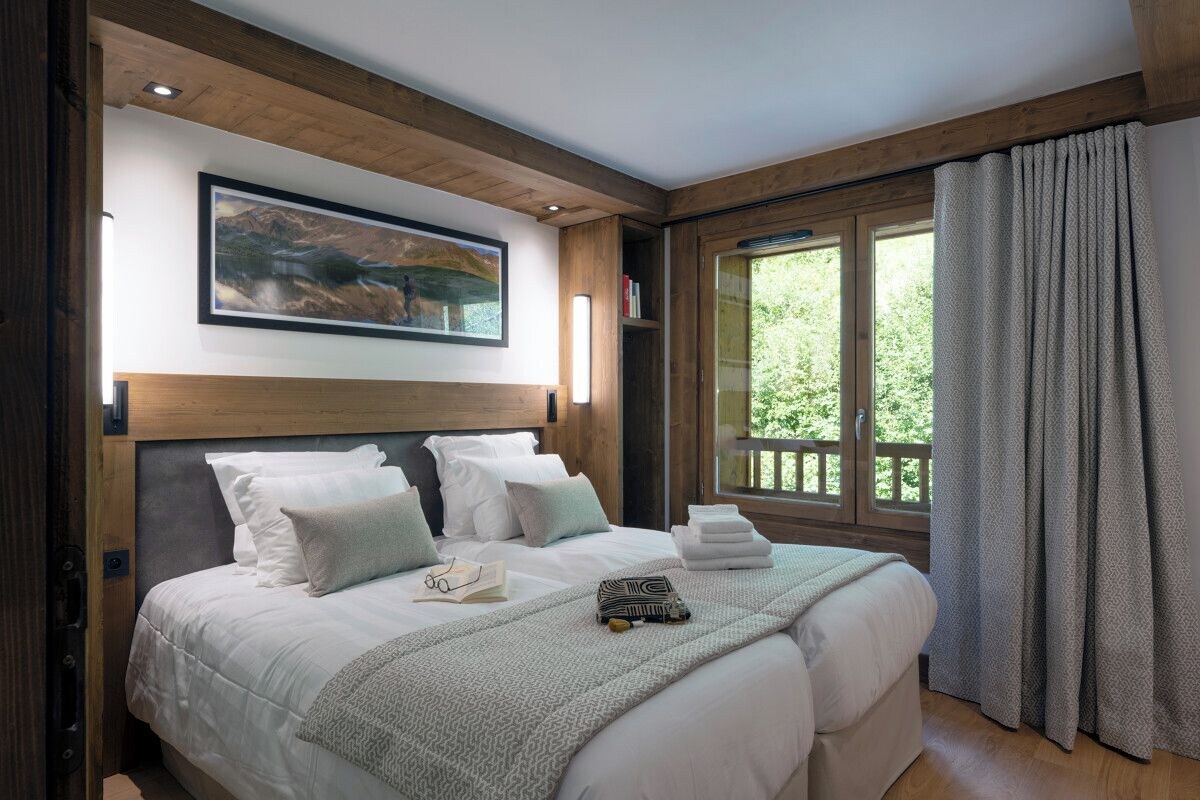 Un dormitorio con una cama grande, un cuadro sobre la cama, una ventana con cortinas y vistas a zonas verdes.