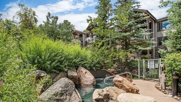 A resort with a natural pool surrounded by large rocks and lush greenery.
