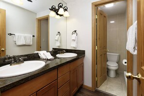 Ein Badezimmer mit zwei Waschbecken, einem Spiegel und einer Toilette.