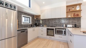 Una cocina moderna con electrodomésticos de acero inoxidable, un respingo de azulejos y estantes de madera.
