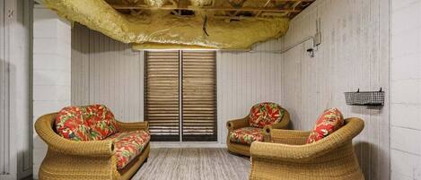 A room with two wicker chairs, a patterned rug, and a wooden ceiling.