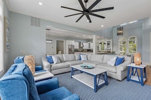 A modern living room with a grey sectional sofa, blue armchairs, and a patterned rug.