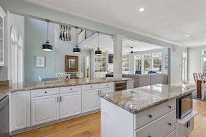 A spacious kitchen with white cabinetry, granite countertops, and pendant lighting.