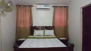 A bedroom with a bed, two nightstands, an air conditioner, and a ceiling fan.