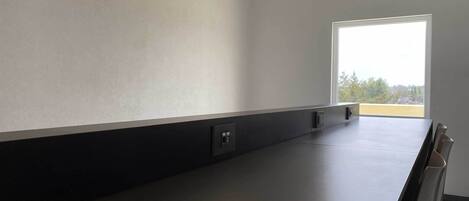 Una habitación moderna con un ventanal grande, una mesa oscura y una silla.