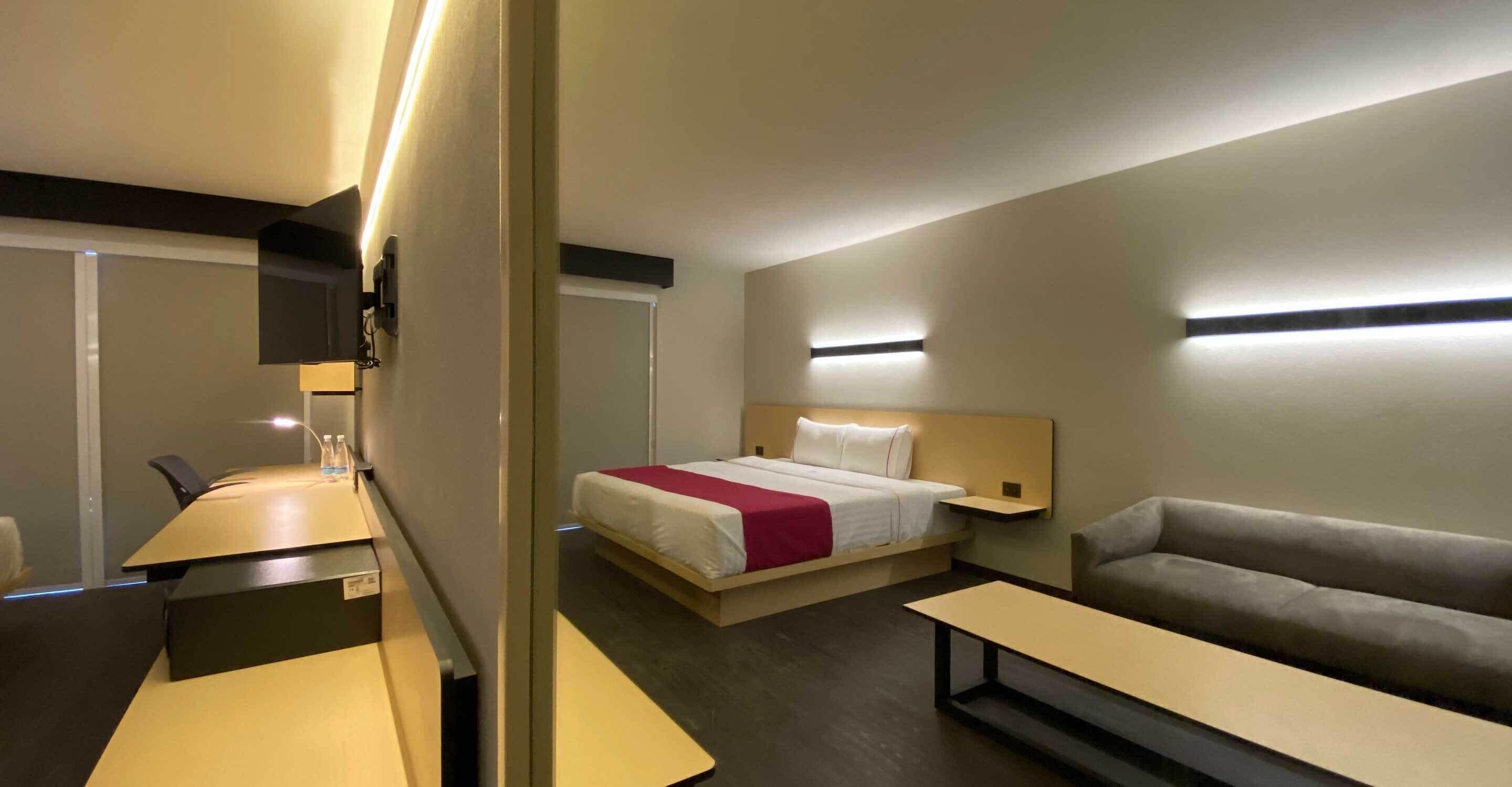 Una habitación de hotel moderna con cama, sofá, escritorio y televisor.