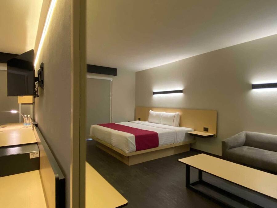 Una habitación de hotel moderna con cama, sofá, escritorio y televisor.