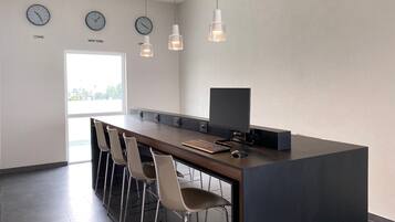 A modern kitchen with a long counter, bar stools, a flat-screen TV, and wall clocks labeled with city names.