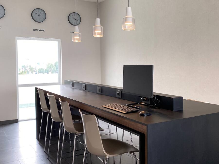 A modern kitchen with a long counter, bar stools, a flat-screen TV, and wall clocks labeled with city names.