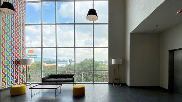 Un hall d’entrée moderne avec de grandes fenêtres, un canapé, des poufs et une table basse.