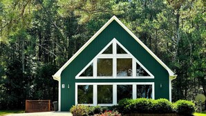Een groen huis met witte details, een huisnummer '2' en een grindpad.