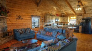Acogedor interior de una cabaña de madera con sala de estar, cocina y comedor.