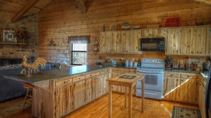 Una cocina rústica con armarios de madera, una chimenea de piedra y una zona de comedor de madera.