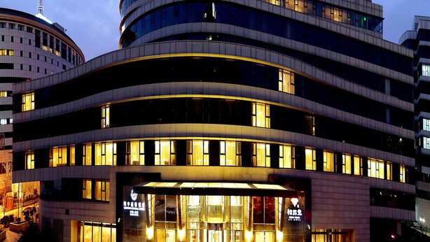 A multi-story hotel with a curved facade, large windows, and illuminated entrance. - Beijing Minyoun Lia! by Minyoun Hotel (Wangfujing Commercial Street Dongdan Subway Station) (Beijing)