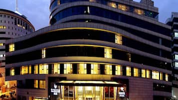 A multi-story hotel with a curved facade, large windows, and illuminated entrance.