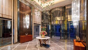 A modern lobby with a marble floor, a round table with a vase of flowers, and a wooden bench. - Beijing Minyoun Lia! by Minyoun Hotel (Wangfujing Commercial Street Dongdan Subway Station) (Beijing)