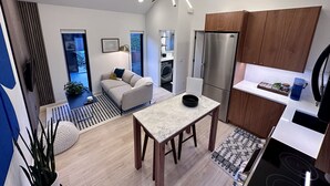 A modern kitchen with a built-in refrigerator, wooden cabinets, and a dining area with a marble table. - Greenwood Getaway - Modern and New, Walk to Shops (Seattle)