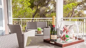 Ein Balkon mit Korbmöbeln, einer Flasche Moet & Chandon Champagner und einem Tablett mit Gläsern und Blumenarrangements.