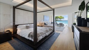 Een moderne slaapkamer met een hemelbed, uitzicht op de oceaan en een minimalistische inrichting.