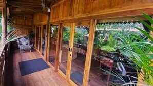 Une terrasse en bois avec des portes vitrées donnant sur un jardin.