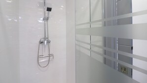 Een moderne badkamer met een douchecabine van glas, een handdouche en een wandmengkraan.