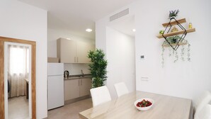 Une cuisine moderne avec des meubles blancs, une table à manger avec des chaises et une étagère murale décorative.