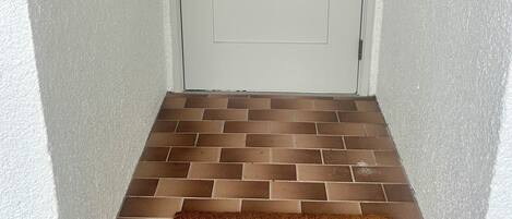 A white door with the number 152, a digital lock, and a brown doormat with 'WELCOME' engraved.
