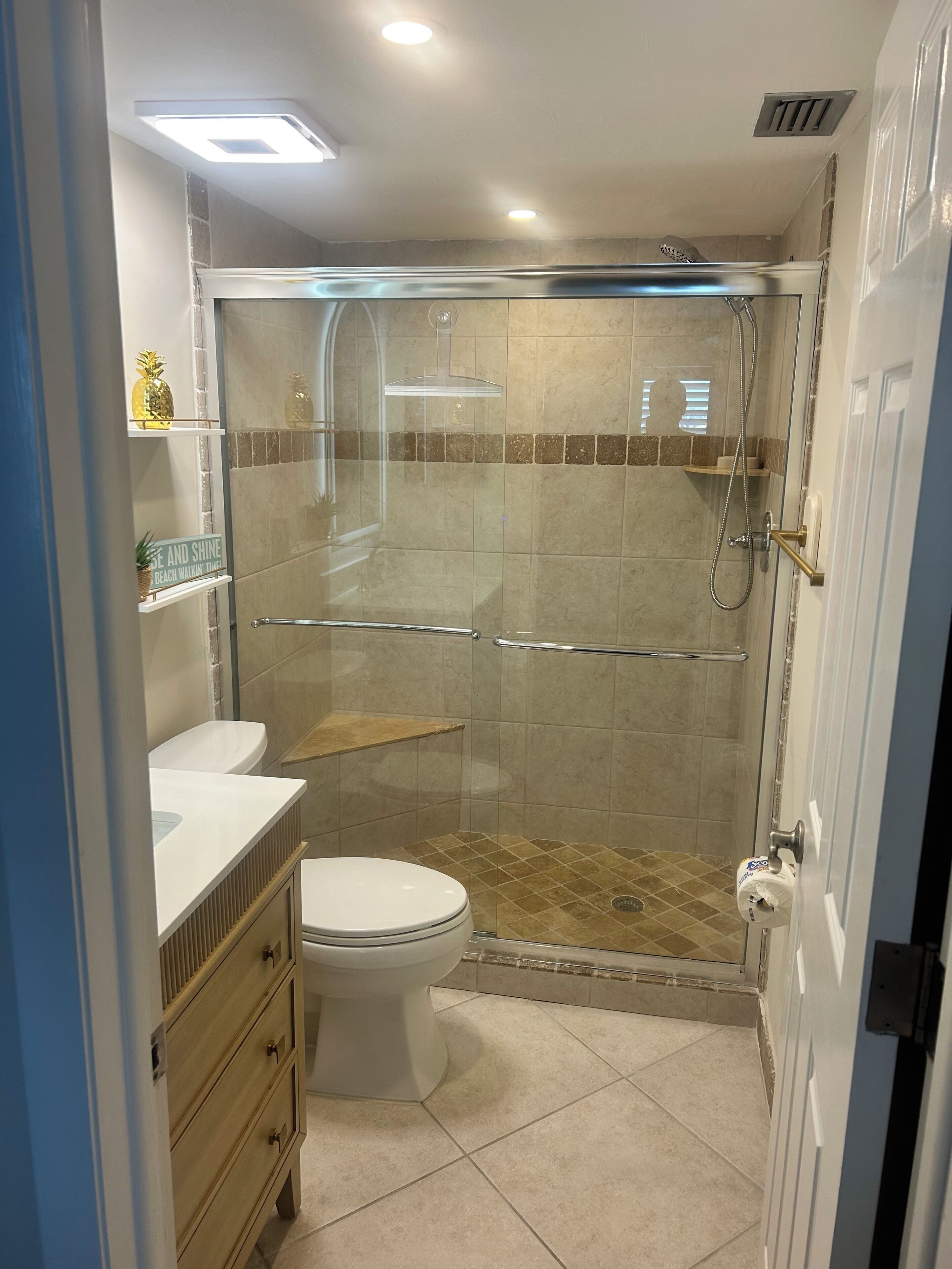 A bathroom with a glass-enclosed shower, a toilet, a vanity with a sink, and a towel rack.