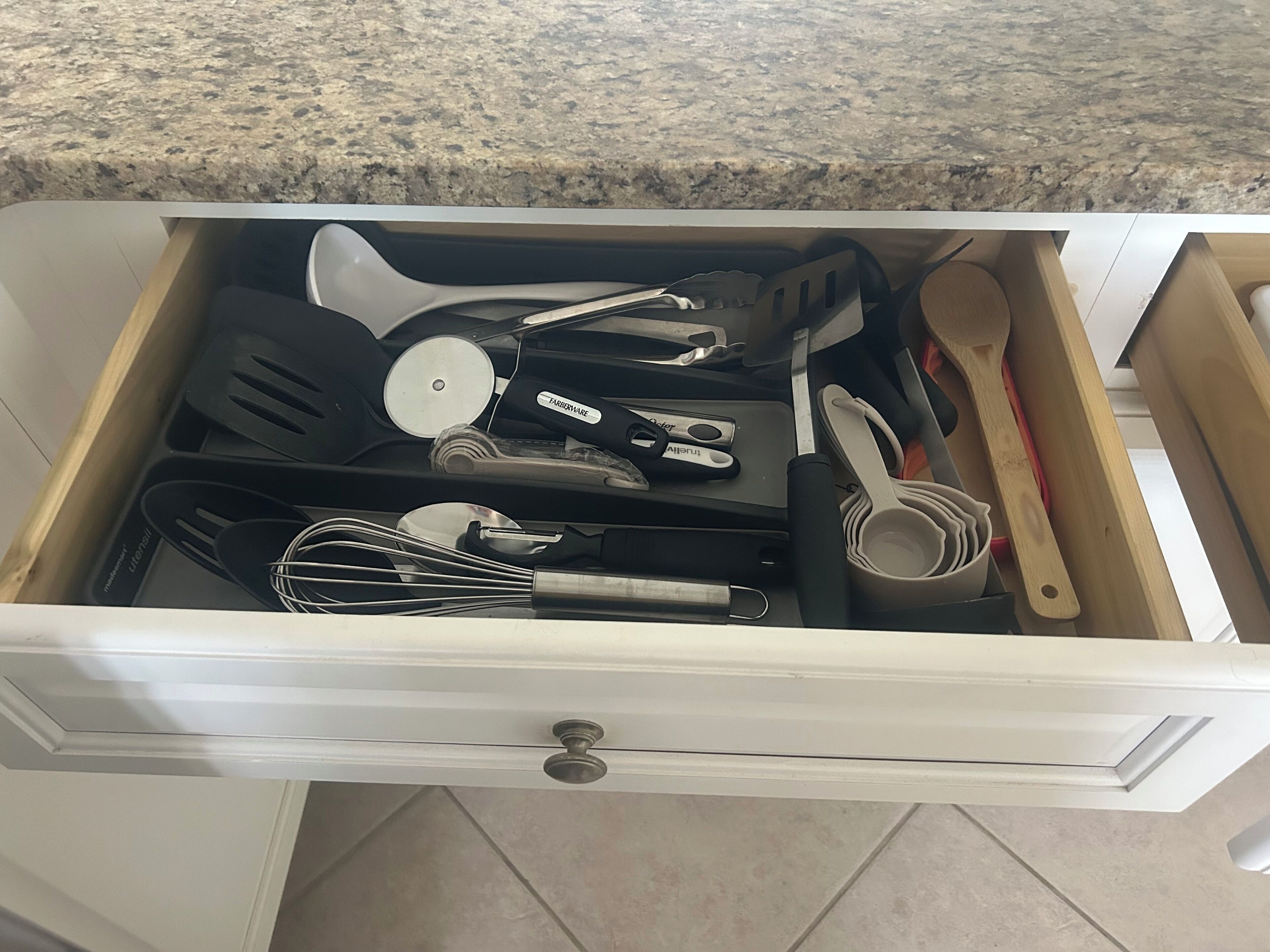 A kitchen drawer with various utensils and cookware.