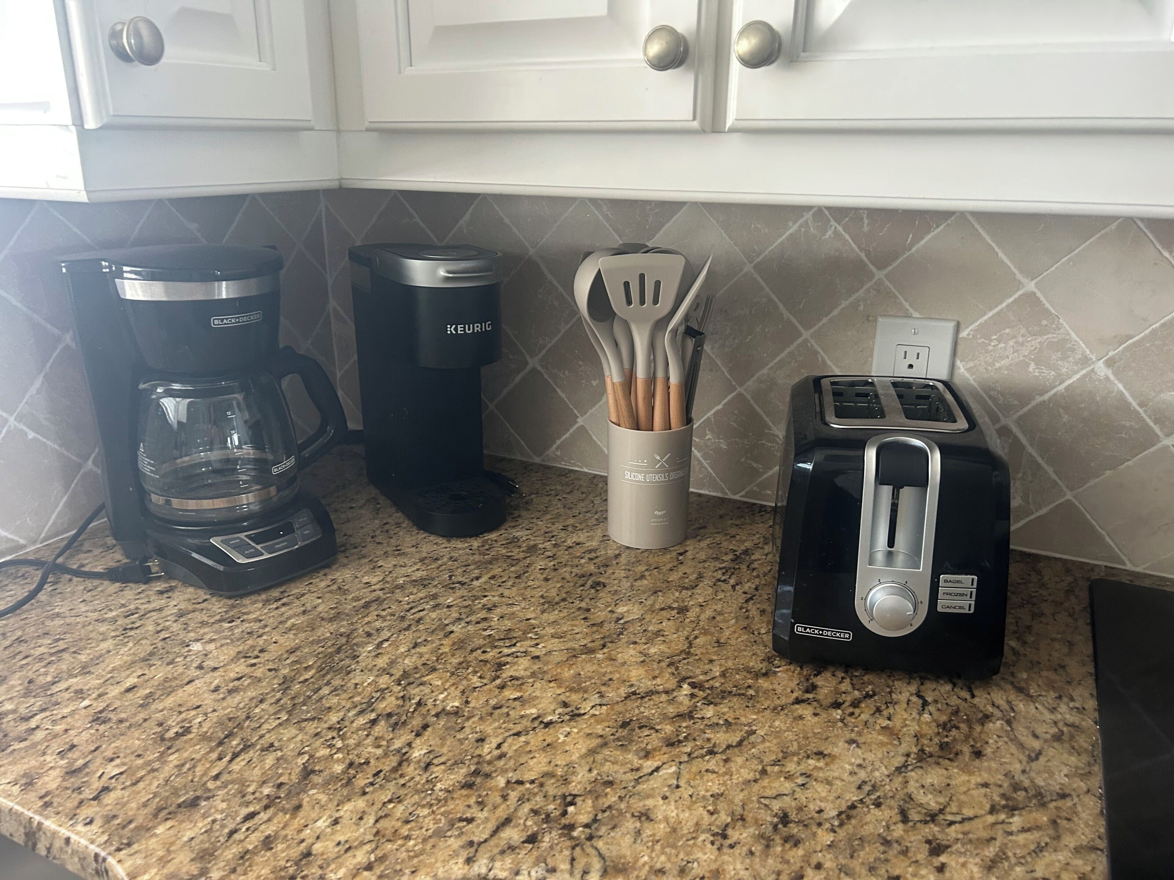 Un piano di lavoro in cucina con una macchina per il caffè, un tostapane e un portau tenzili.