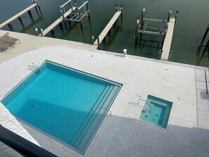 Une piscine avec un petit bassin attenant, une terrasse en bois et une jetée qui s’avance dans l’eau.