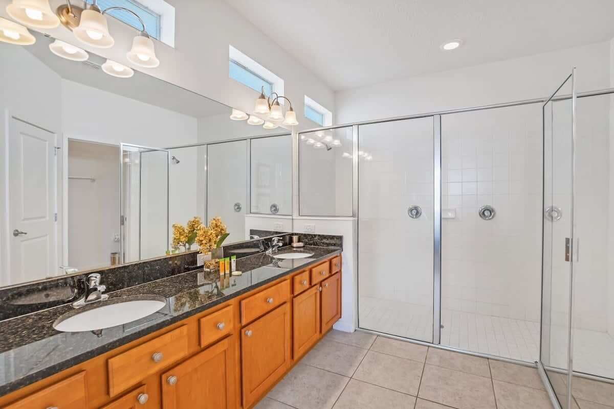 A modern bathroom with a large mirror, a double sink vanity, and a walk-in shower.