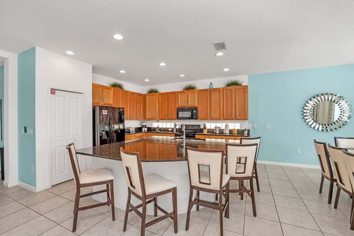 A modern kitchen with wooden cabinets, a central island, and bar stools.