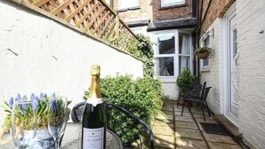 A bottle of wine on a table with a view of a brick building and a wooden fence. - Ground Floor At The Lawns - Lovely chic ground floor apartment (Filey)