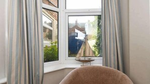 A room with a large window, a small table with a chair, and curtains. - Ground Floor At The Lawns - Lovely chic ground floor apartment (Filey)