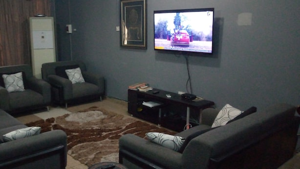 A living room with two sofas, a coffee table, a TV, and a cabinet. - Short Stay Apartment (Accra)