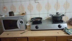 A kitchen with a microwave, a gas stove, and a pot on the stove. - Short Stay Apartment (Accra)