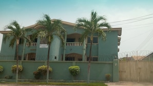 A multi-story building with a sign indicating it is the M.P. Hadjio Court. - Short Stay Apartment (Accra)