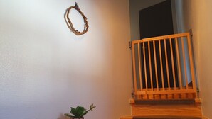 Un escalier en bois avec une rampe en métal, une petite plante en pot sur la plateforme et une guirlande décorative accrochée au mur.