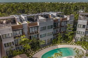 A modern hotel with multiple floors, outdoor swimming pool, and lush greenery surrounding the property.