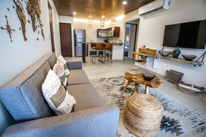 A modern living room with a grey sofa, a coffee table, and a TV mounted on the wall. - Macondo Tulum  (Tulum)